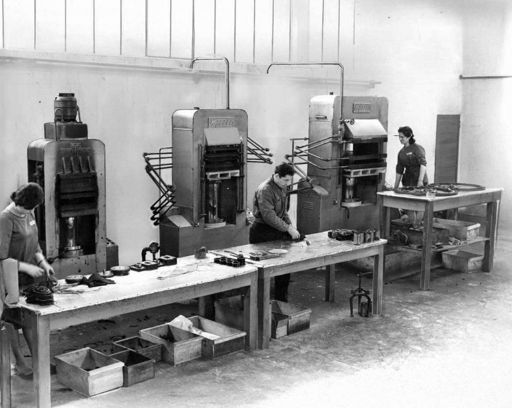 Foto in bianco e nero degli anni 60 di un'azienda di produzione di guarnizioni in gomma con operai che lavorano manualmente la gomma